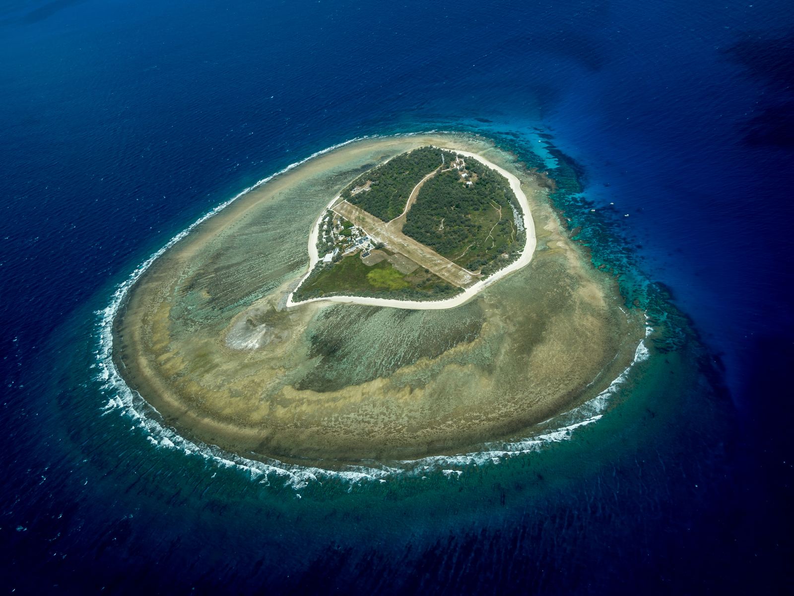 Aerial view of a reef island ringed by turquoise water