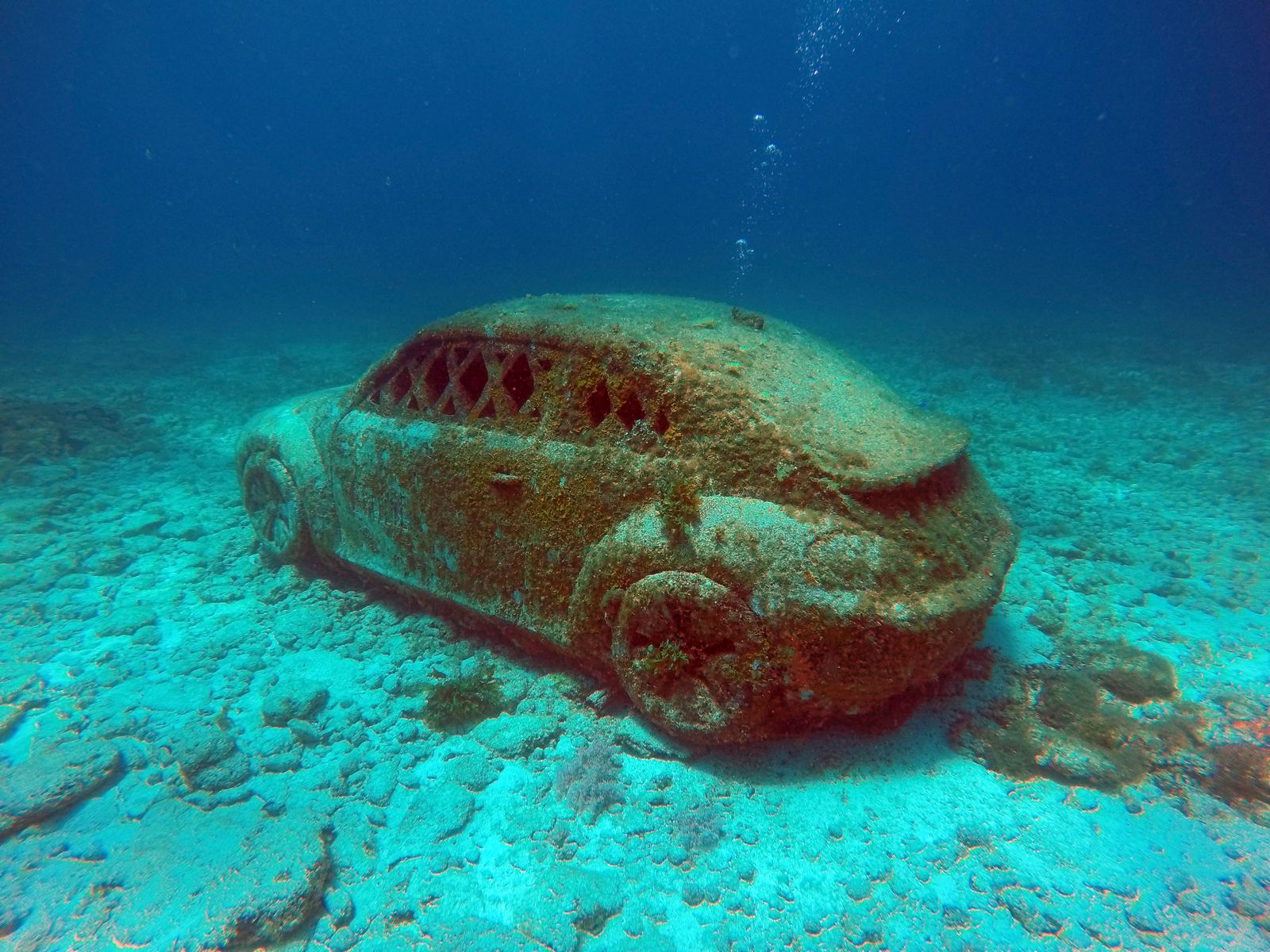 An underwater sculpture of a car, covered in marine growth